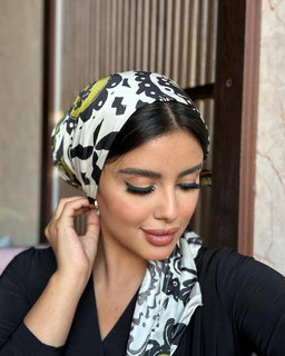 A woman wearing a headscarf and black top, exuding elegance and grace.