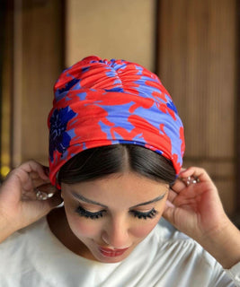 A woman wearing a turban with a red and blue print, showcasing cultural diversity and vibrant colors.