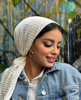 A woman in a headscarf and denim jacket standing outdoors.
