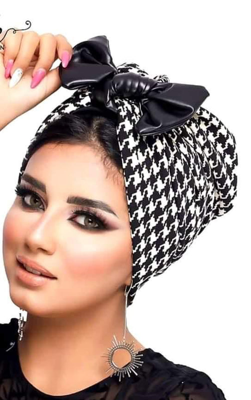 An elegant lady with a black and white checkered head wrap, showcasing her fashion sense.